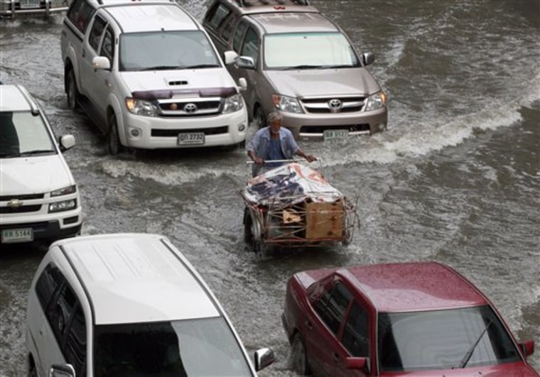 Motorists make their way through a flooded street caused by heavy overnight rain Saturday, Oct. 8, 2011 in Bangkok, Thailand. (AP Photo/Apichart Weerawong)